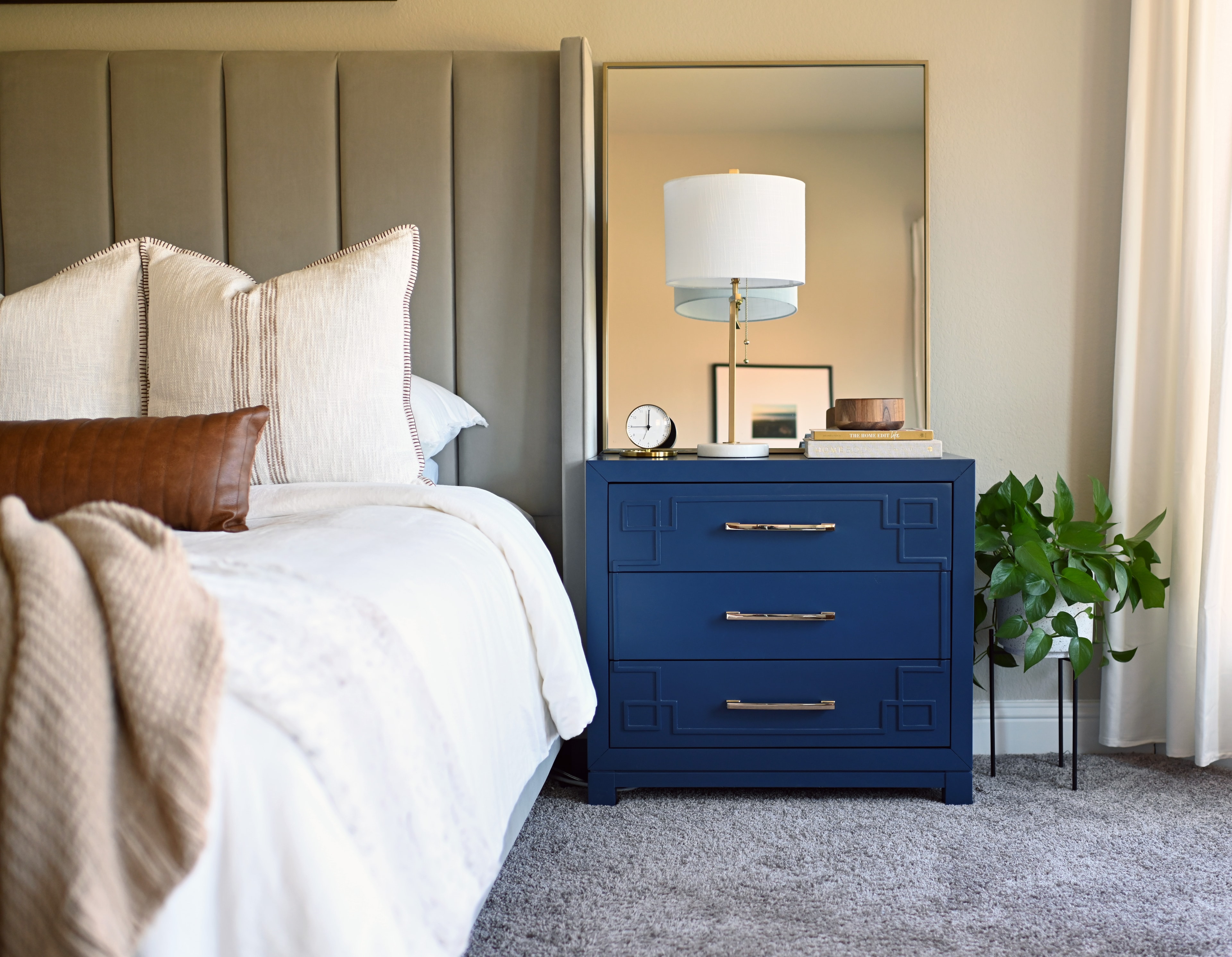 Primary bedroom with upholstered headboard and navy blue nightstand