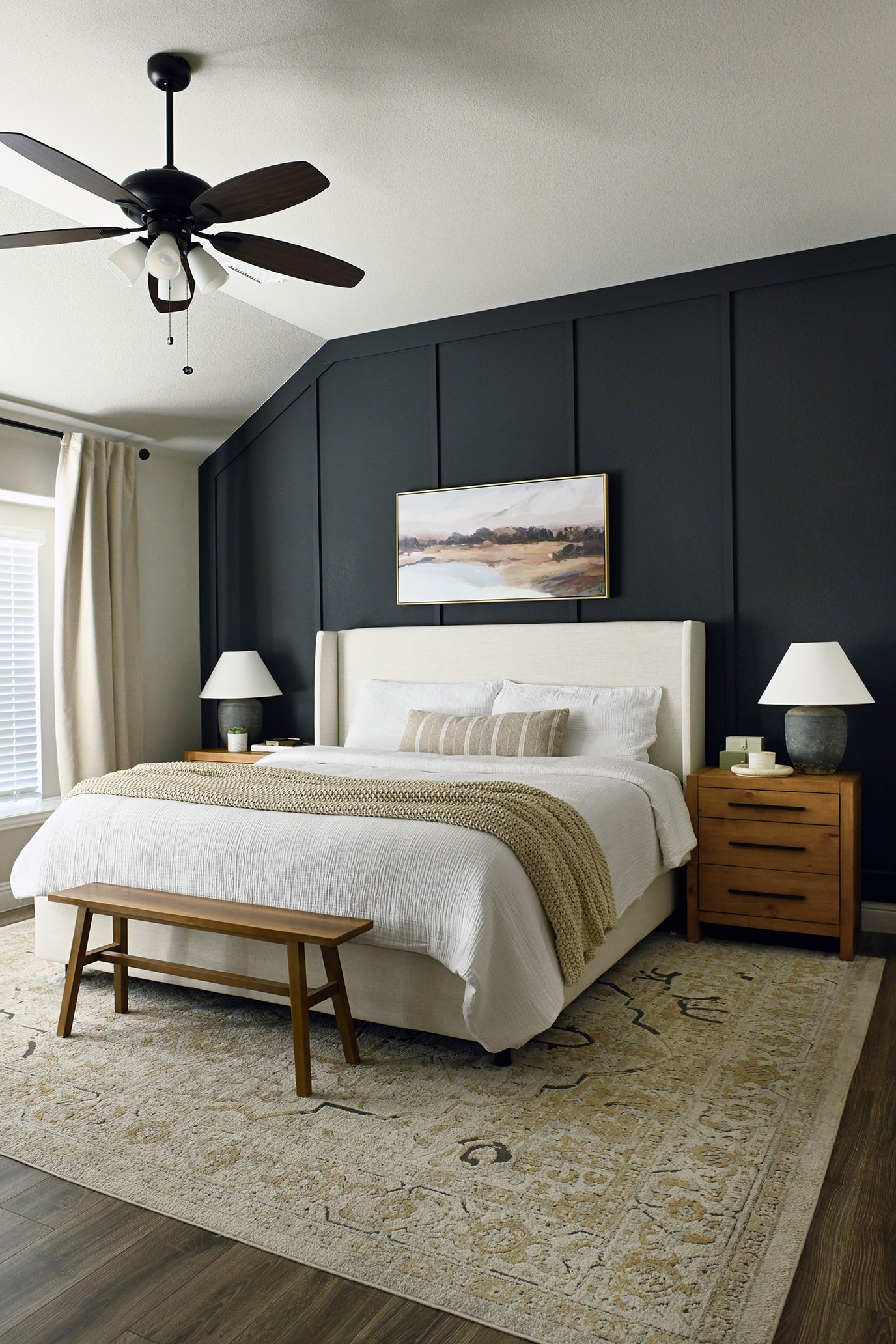 Primary bedroom with dark accent wall, upholstered headboard, and wood nightstands