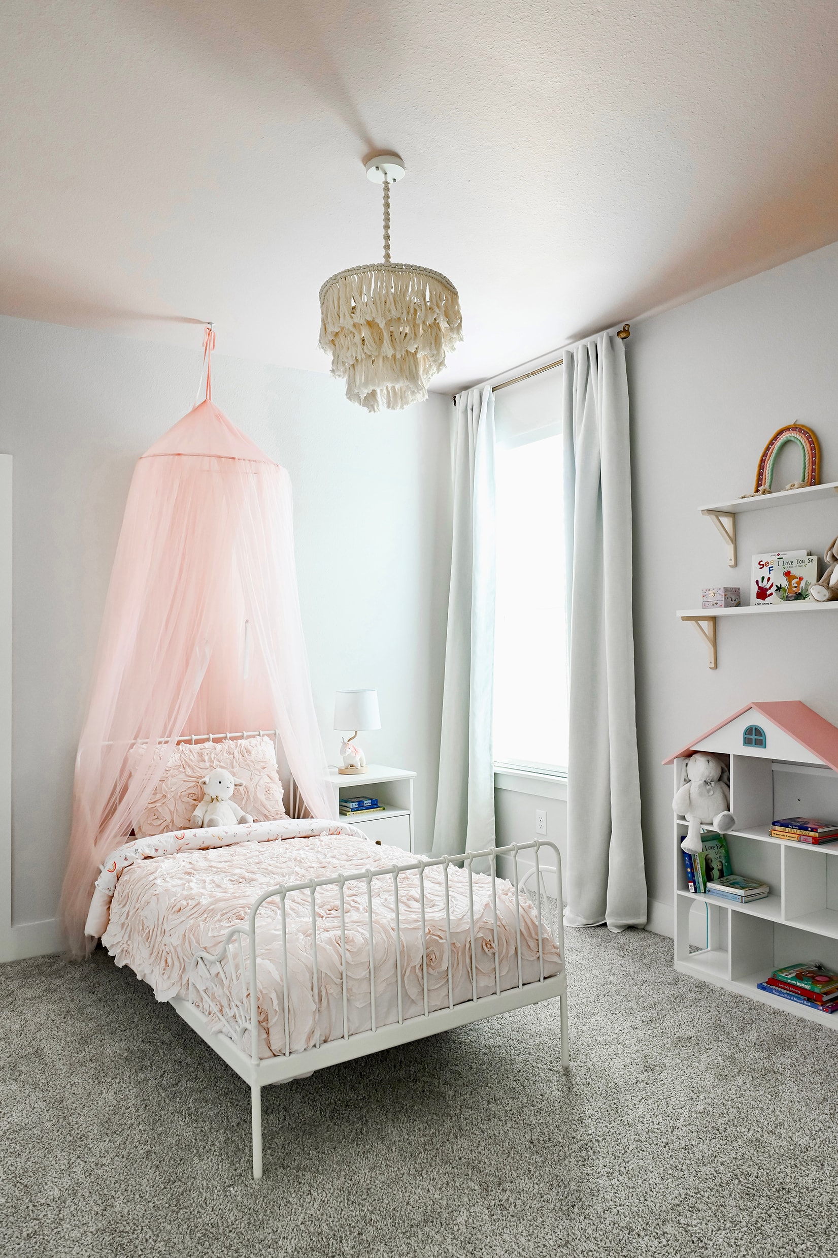 Child's bedroom with pink canopy bed and decorative chandelier