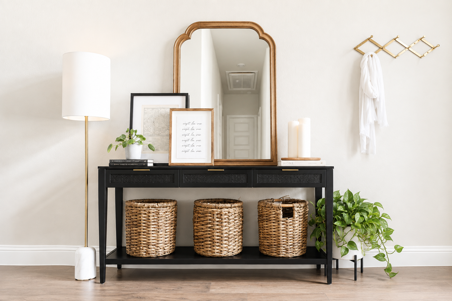 Entryway with black console table, woven baskets, arched gold mirror, and trailing plant