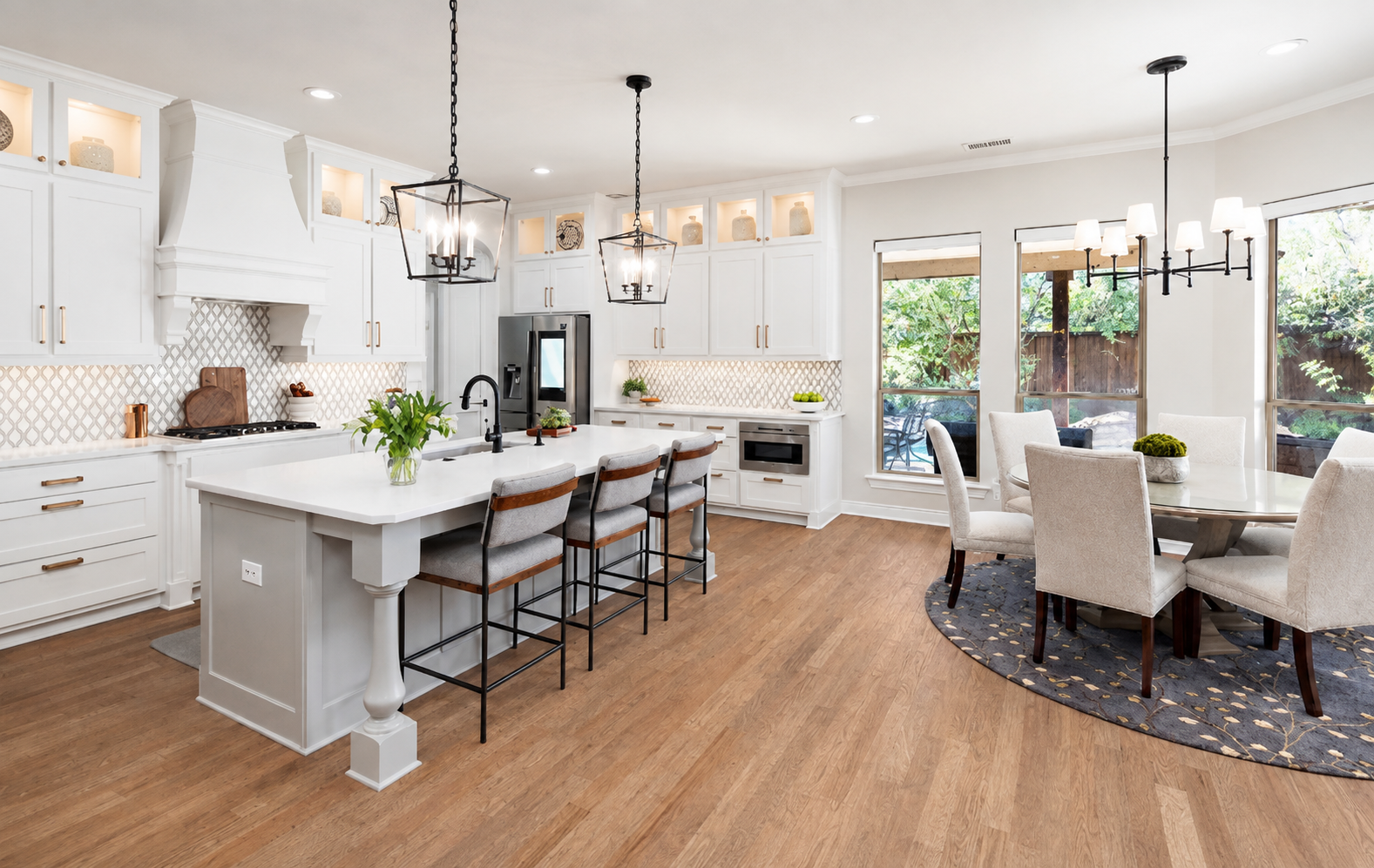 Kitchen and dining area with white cabinetry, gray island, lantern pendants, and hardwood floors