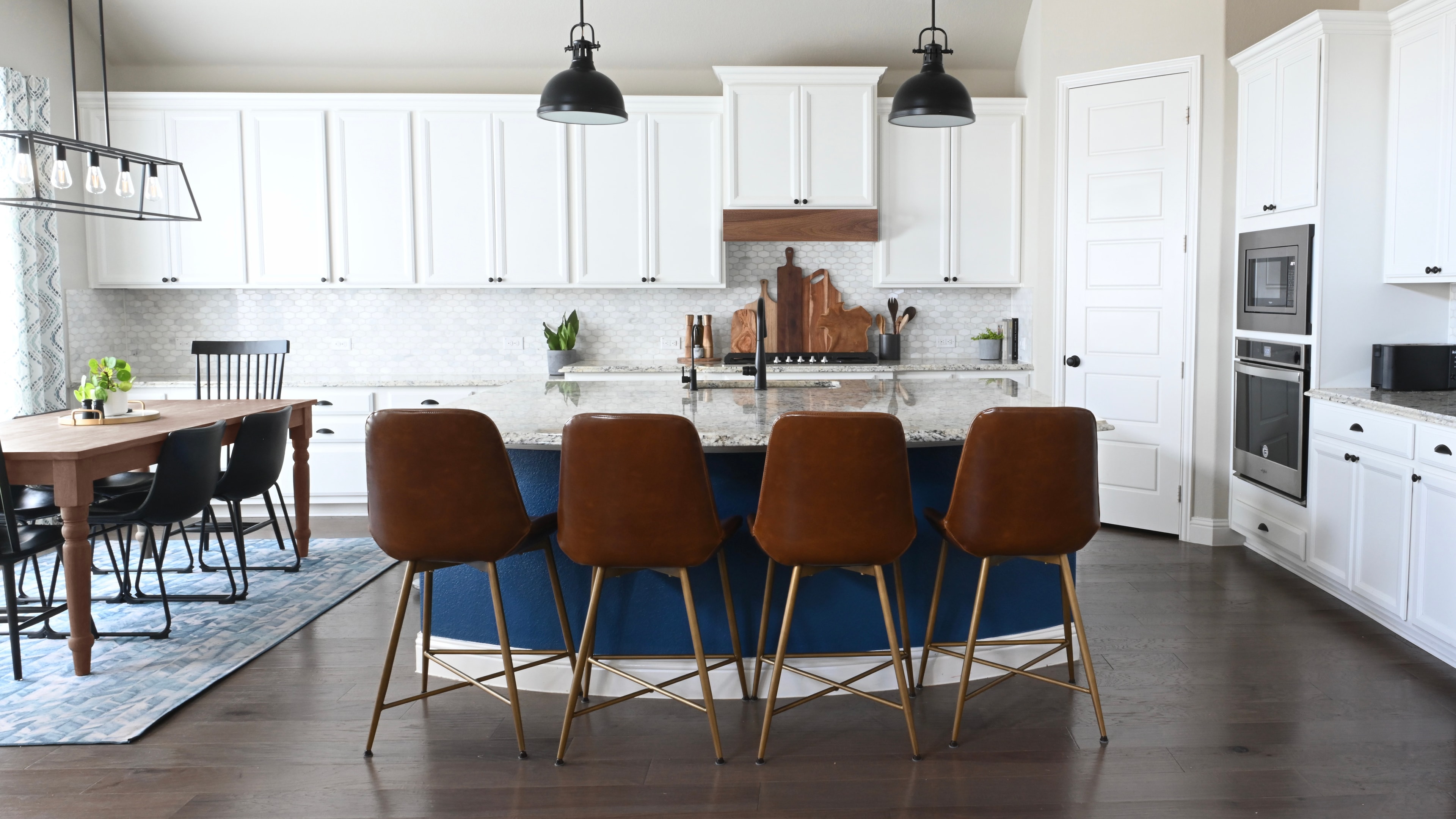 Modern kitchen with white cabinetry, navy island, and leather bar stools