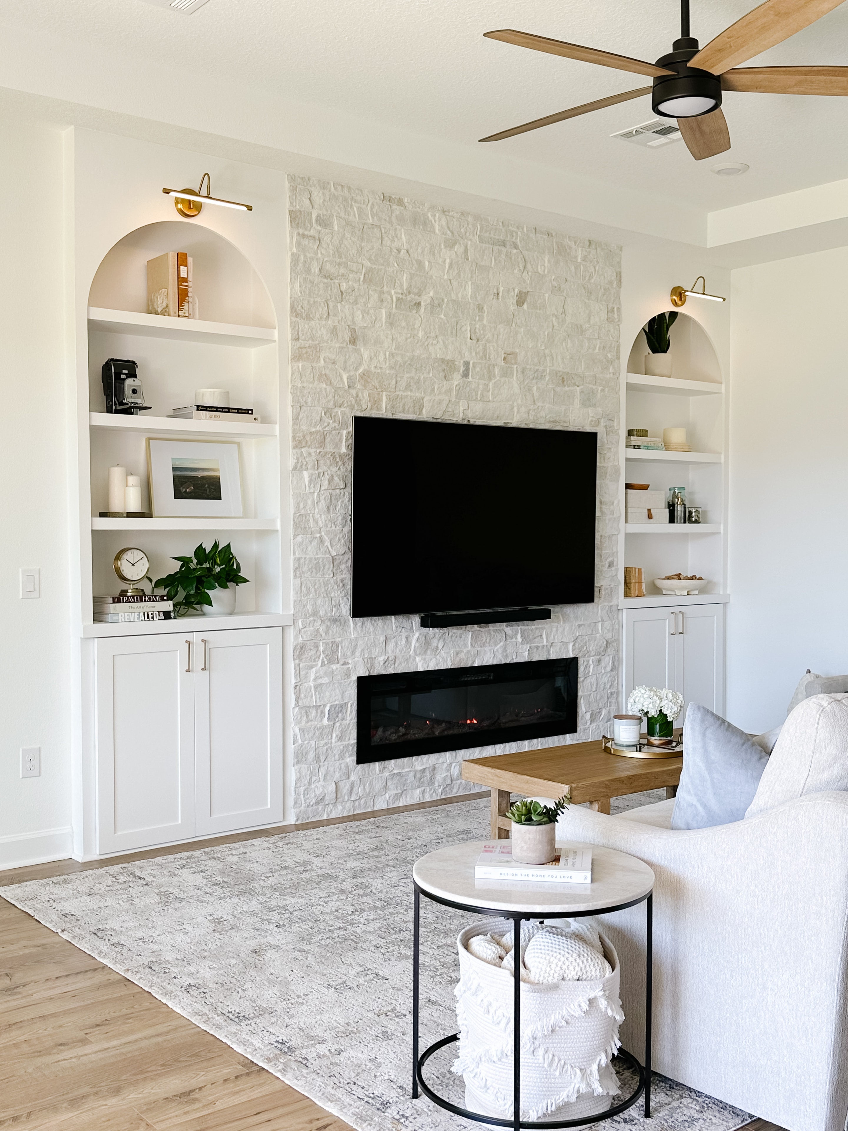 Kitchen with white cabinetry, black lantern pendants, large island with bar stools, and arched doorway