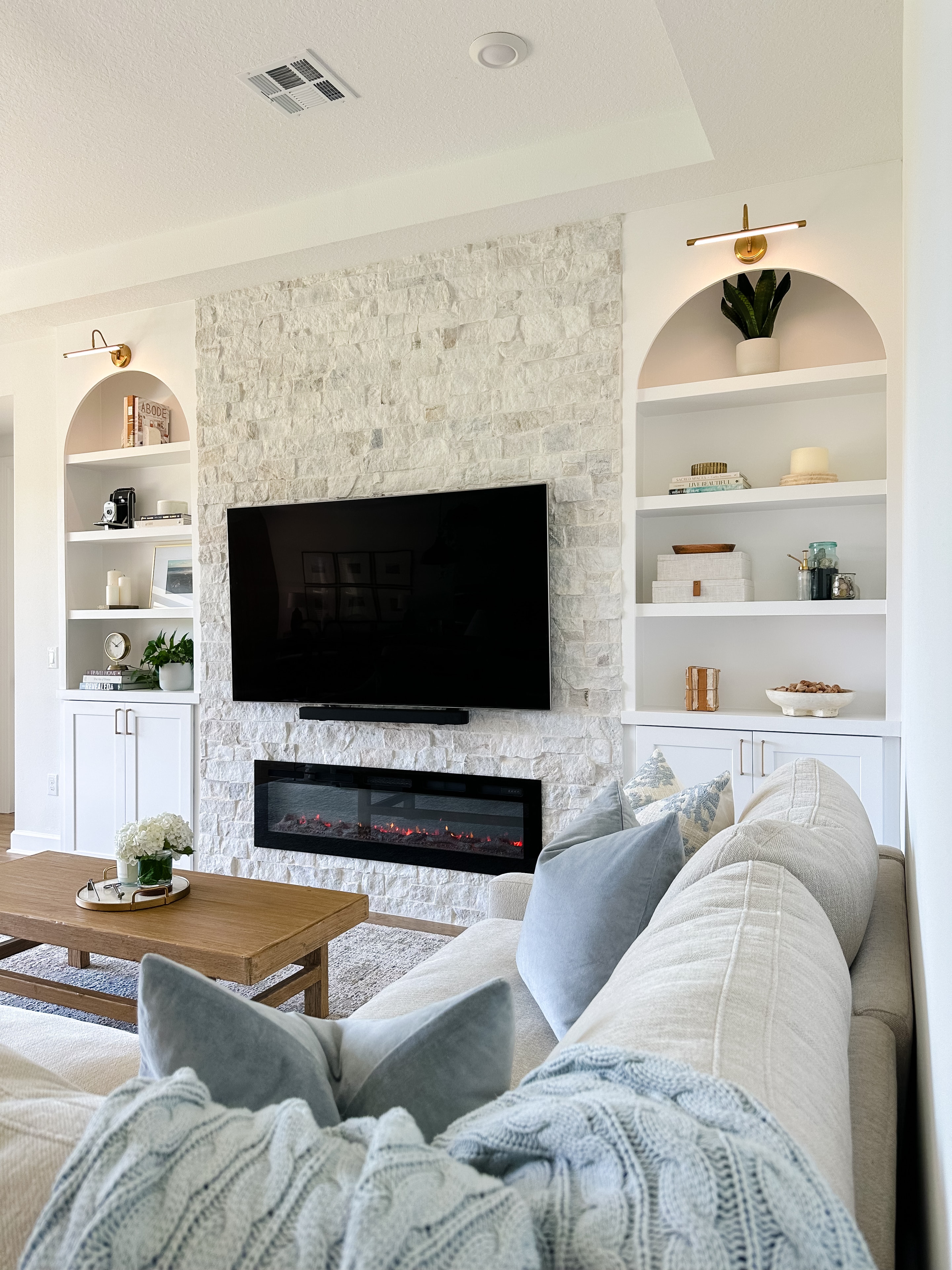 Living room with stone fireplace, built-in shelving, arched niches, and sectional sofa