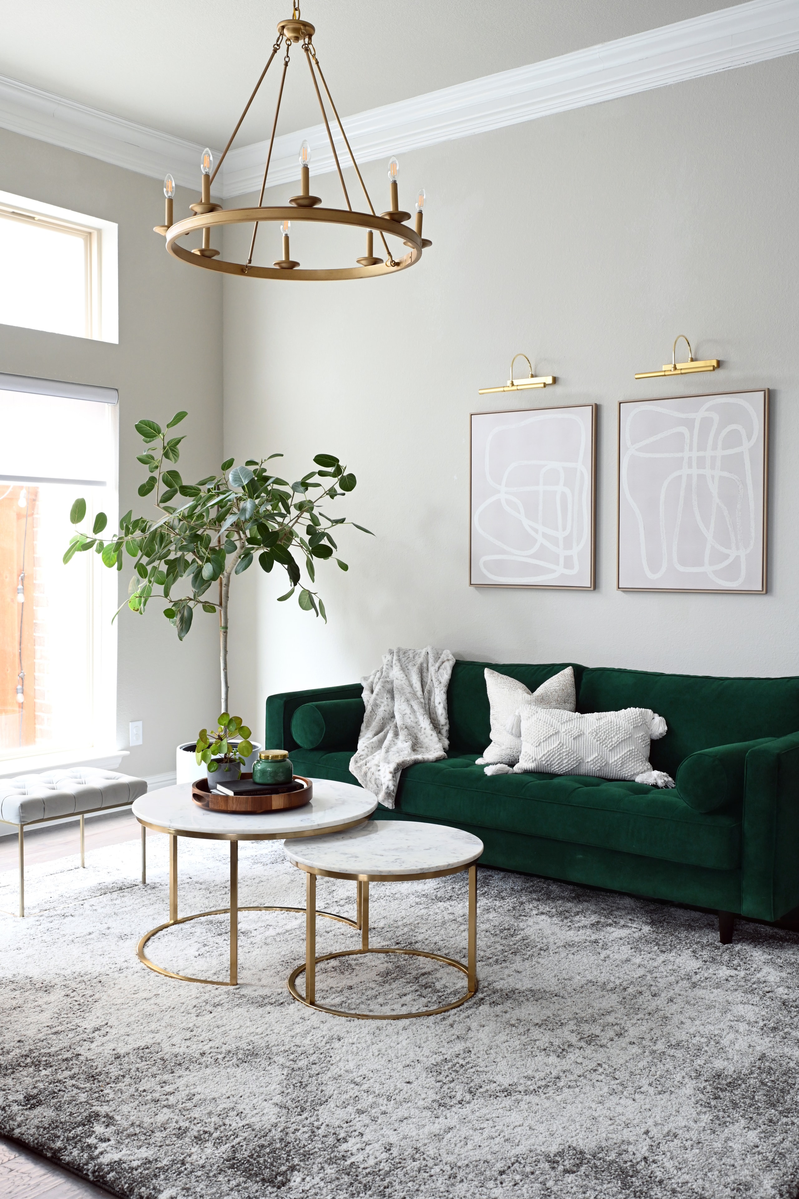 Living room with green velvet sofa, brass chandelier, and marble coffee tables