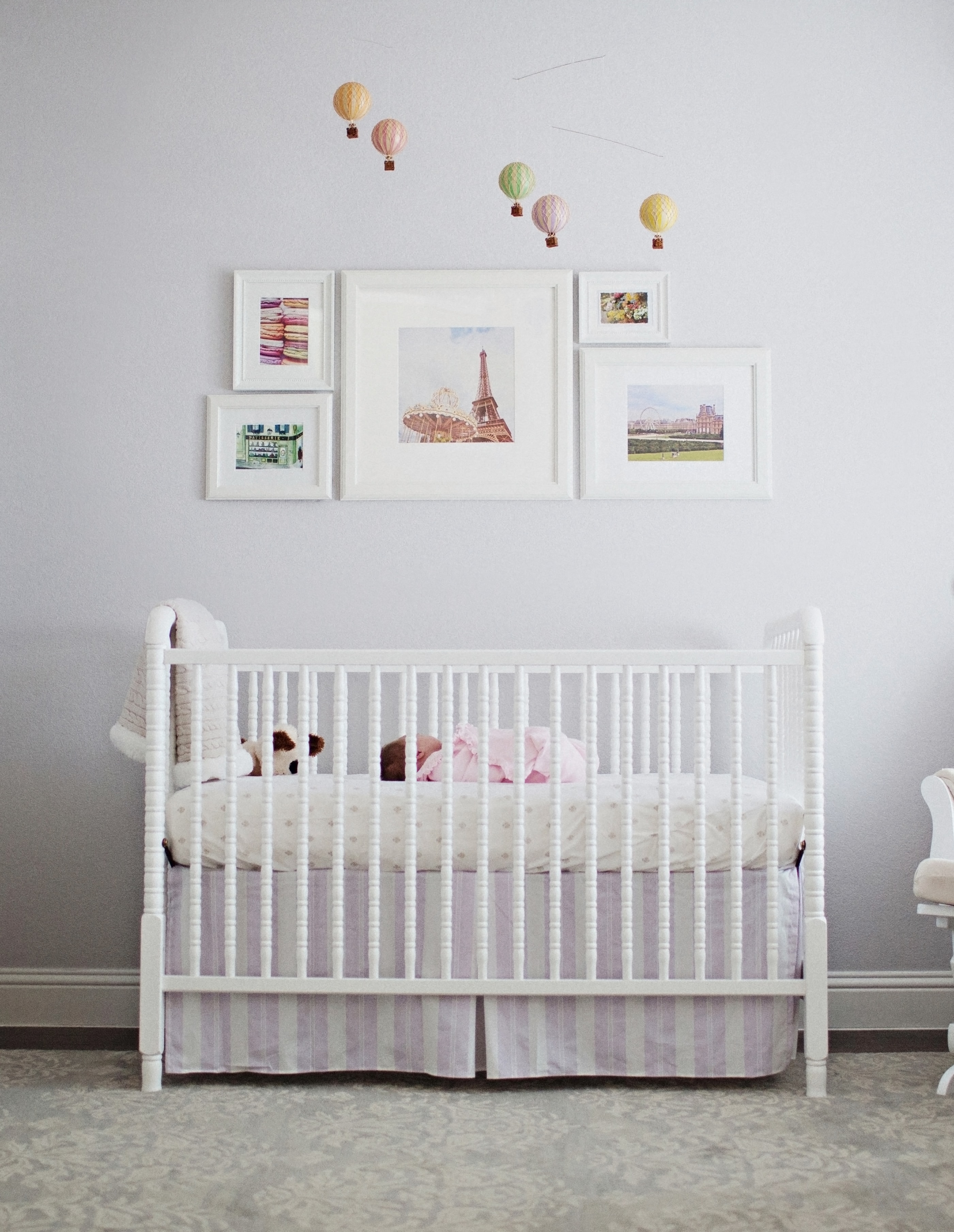 Girl's nursery with Eiffel Tower gallery wall, white crib, and pink accents
