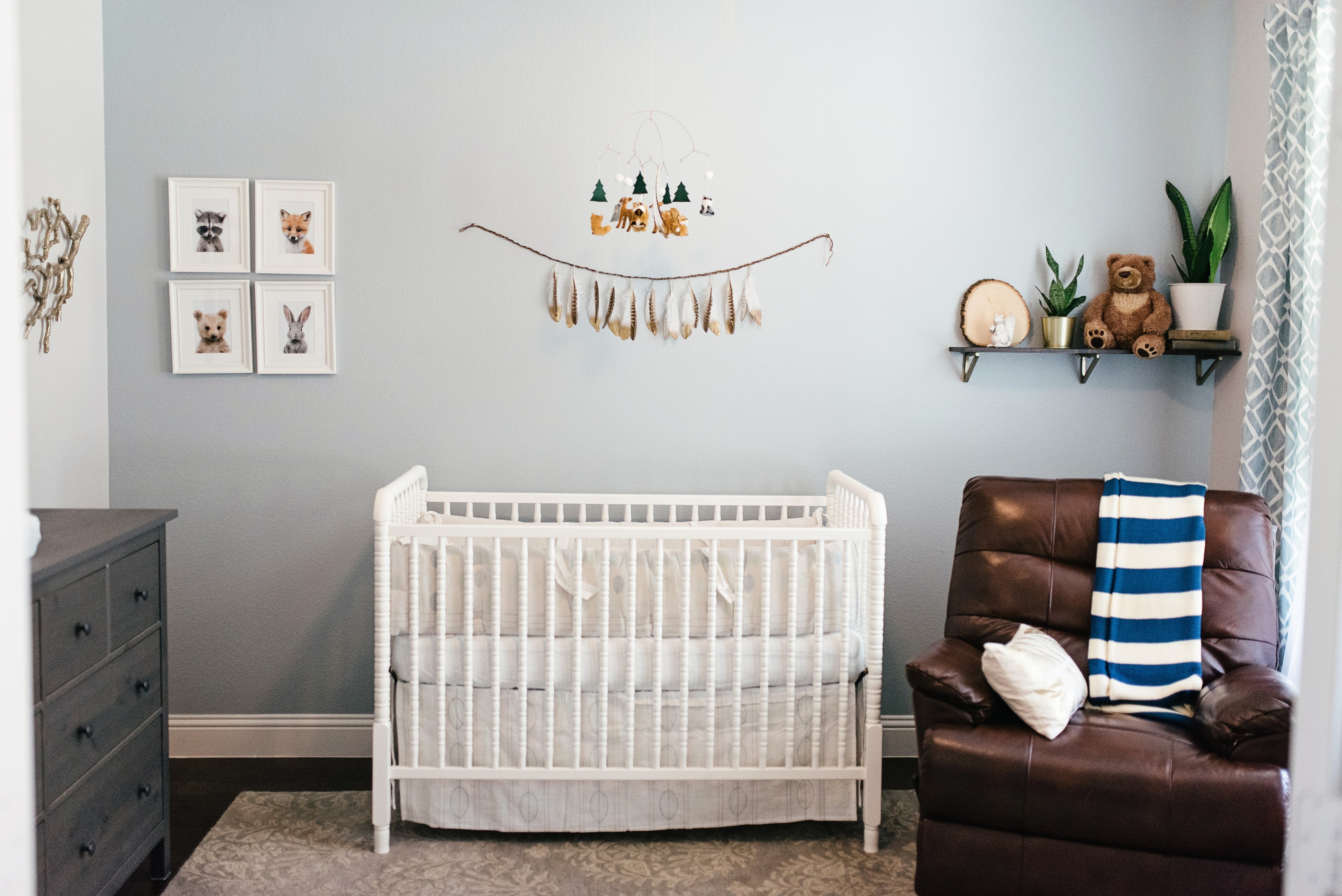 Woodland nursery with leather recliner, white crib, and nature-themed decor