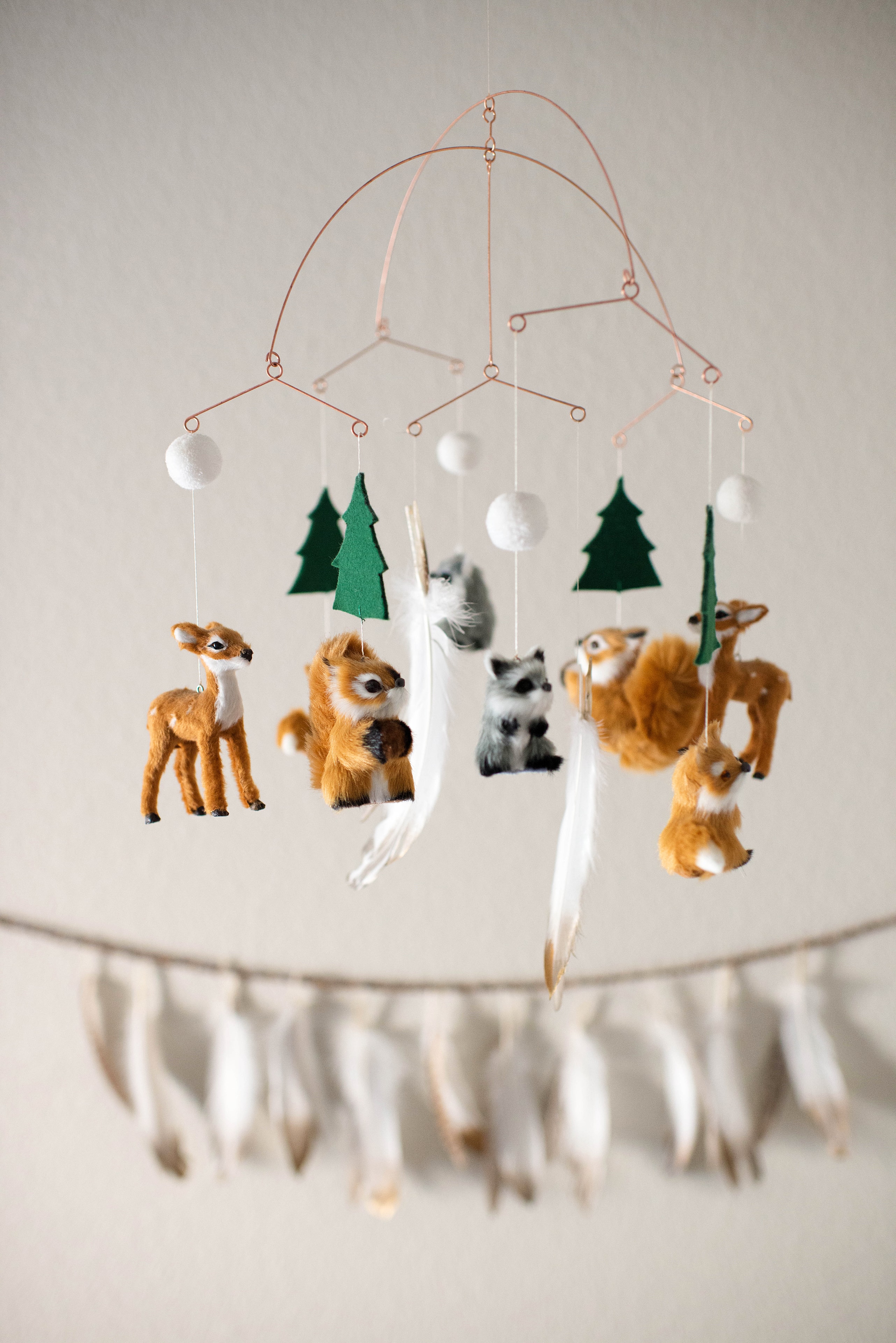 Woodland nursery mobile with deer, foxes, and felt trees hanging above a dreamcatcher garland