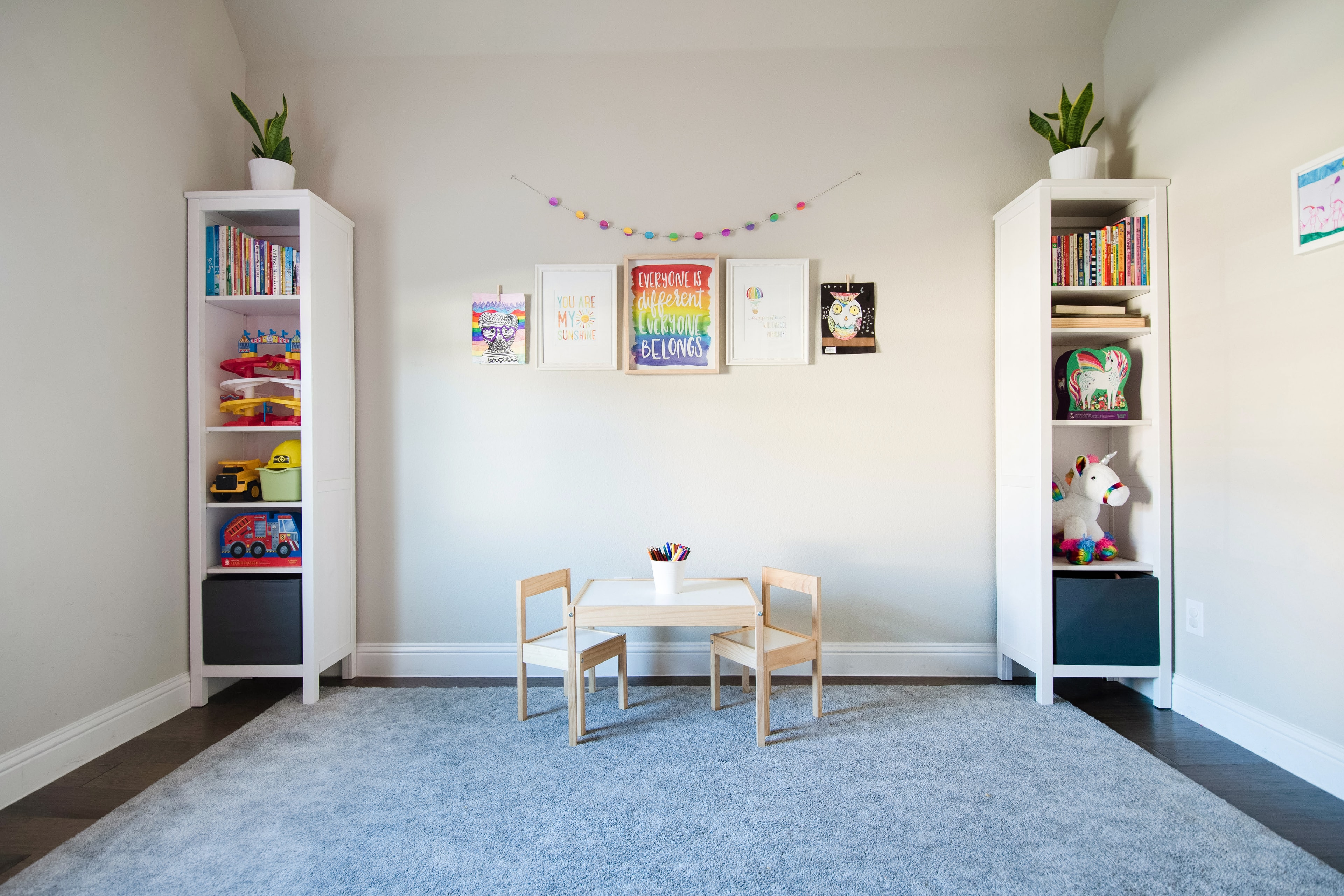 Bright playroom with white bookshelves, children's table, and colorful art